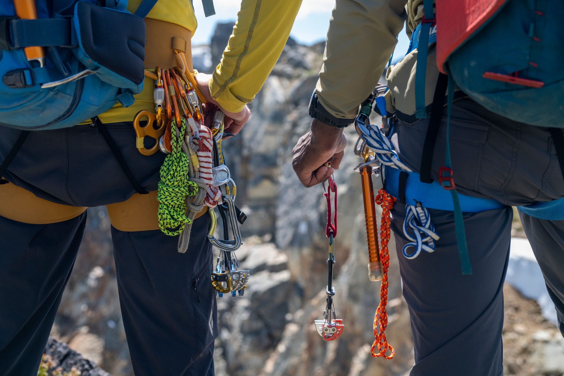 Mid section crop of climbing guide and client on top of mountain