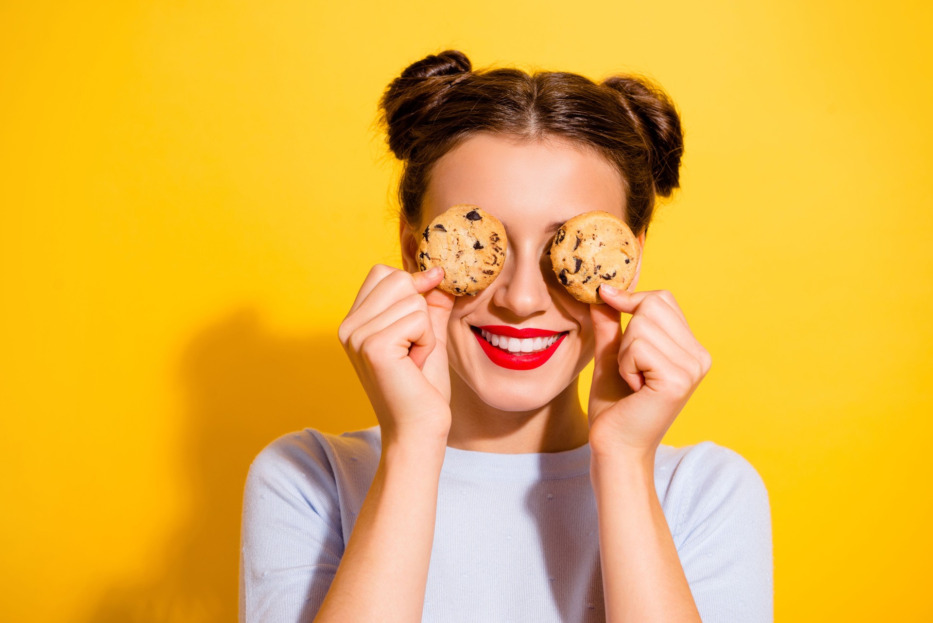 Photo of sweet pretty lady wear long sleeve holding two biscuits close eyes isolated yellow color background