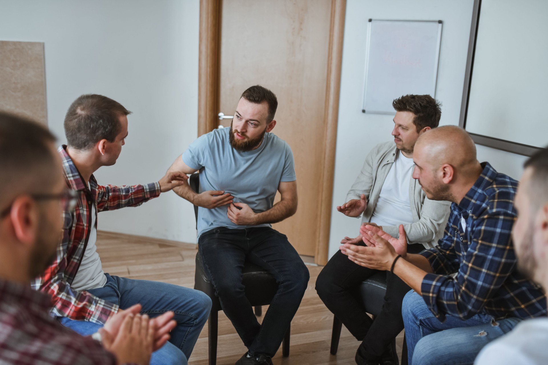 Male Adult Expressing Pain in Group Therapy Session Being Vulnerable While Men Are Applauding
