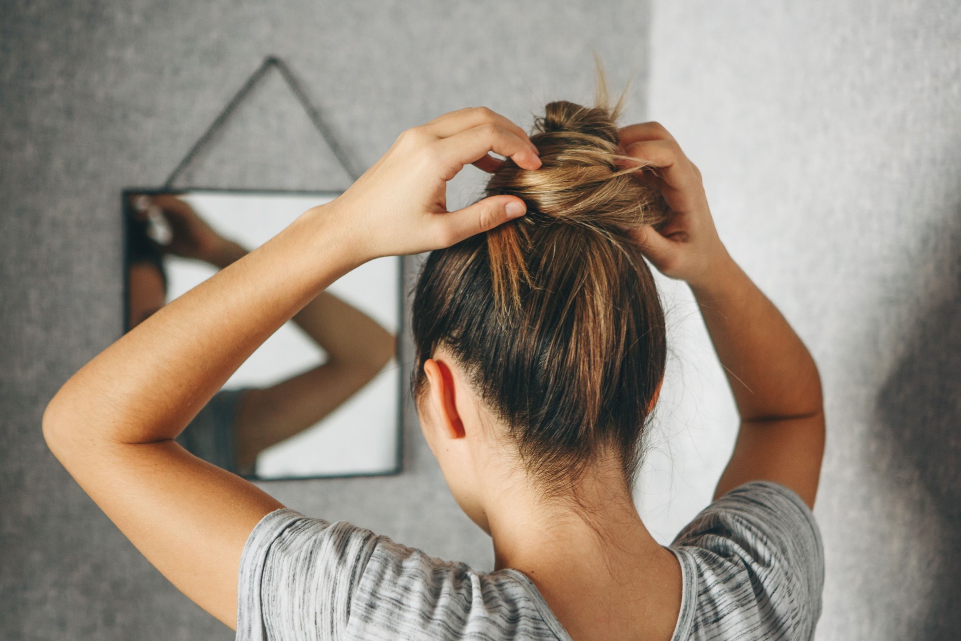 Girl doing hairstyle at the mirror