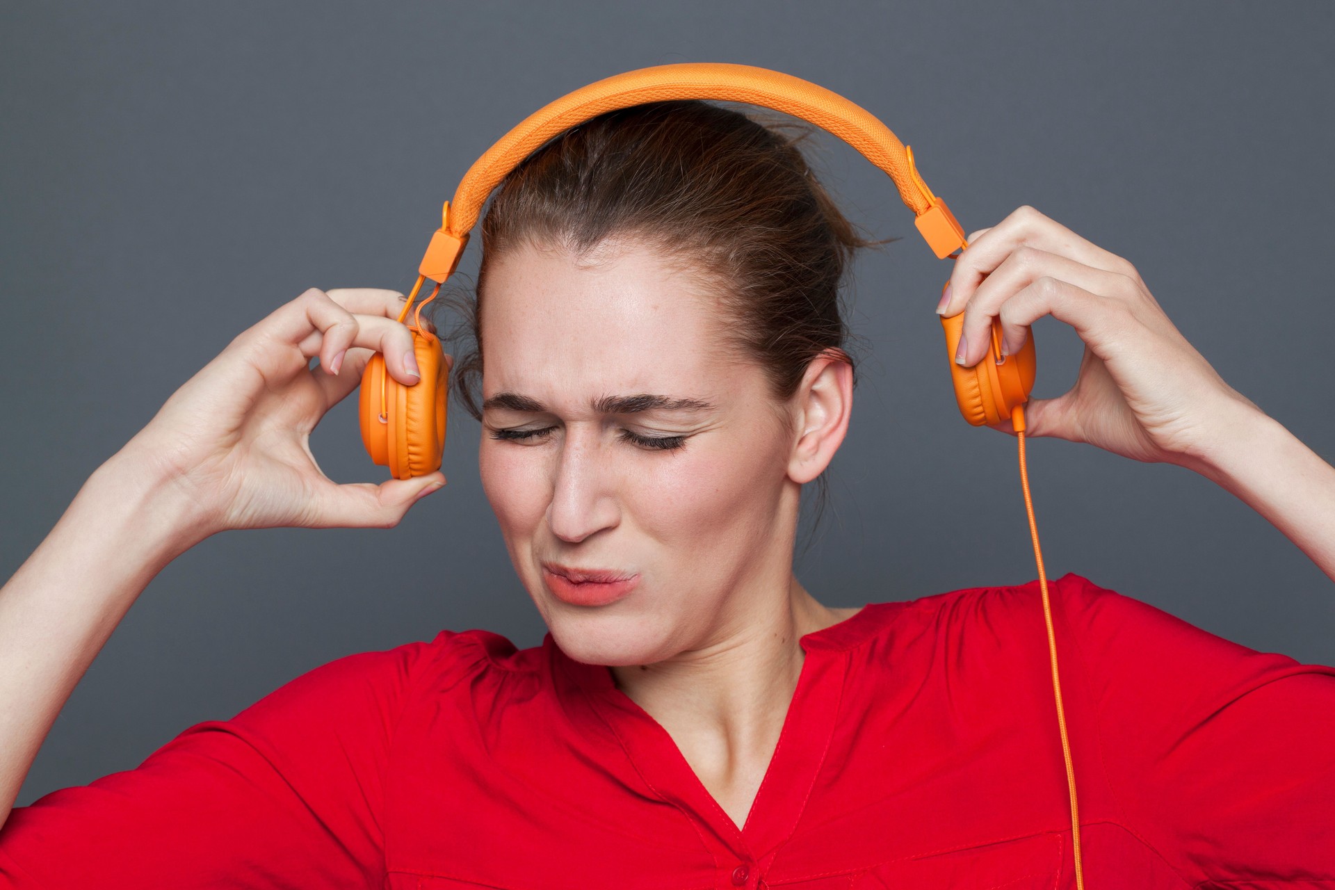 unhappy beautiful young woman suffering from music headache or tinnitus
